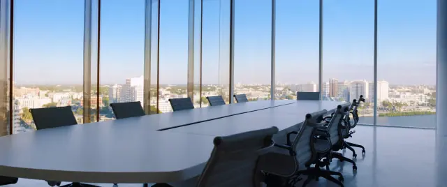 A city skyline at dusk seen from a quiet boardroom window.